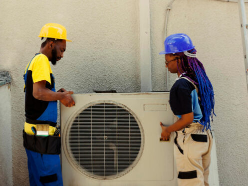 african american engineering coworkers opening up rusty out service air conditioner replace it with new performant outside condenser after draining refrigerant replacing ductwork